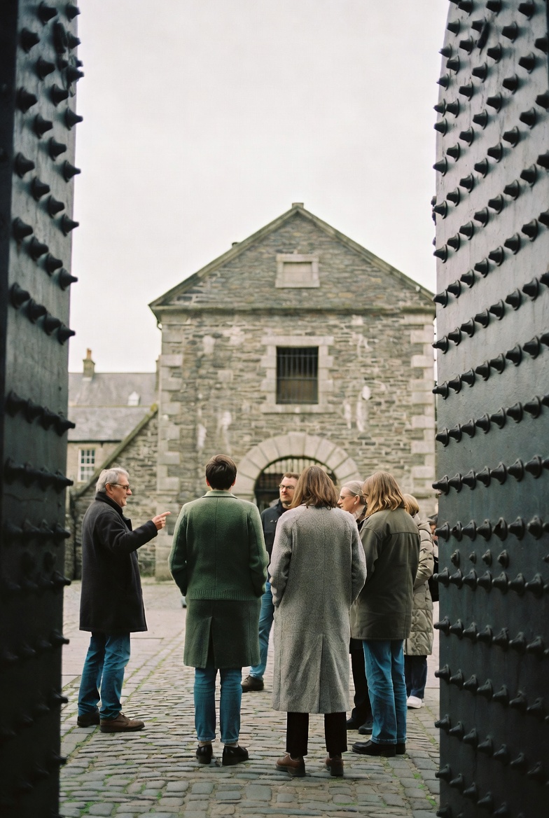 A small Celtic Penitentiary walking group pauses on the cobbled lane outside Kilmainham Gaol on a grey Dublin afternoon.